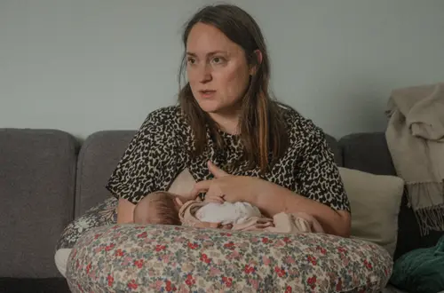 Bébé de quelques mois souriant, emmailloté dans un drap blanc.