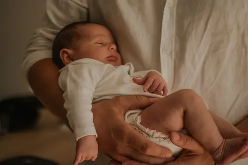 Future maman assise en tailleur, caressant son ventre arrondi.